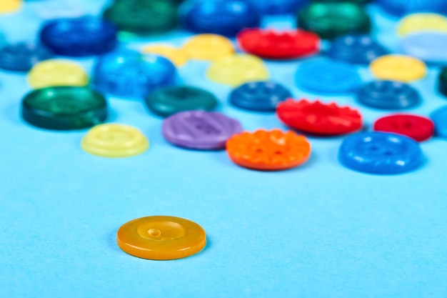 Multicolored buttons for clothess on a blue background Closeup selective focus