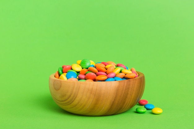 Multicolored candies in a bowl on a colored background birthday and holiday concept Top view with copy space