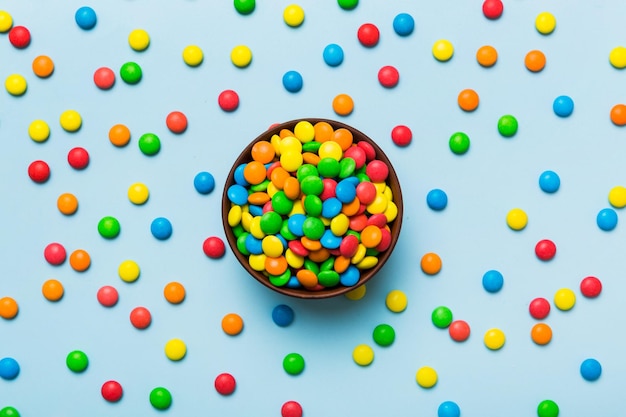 Multicolored candies in a bowl on a colored background birthday and holiday concept Top view with copy space