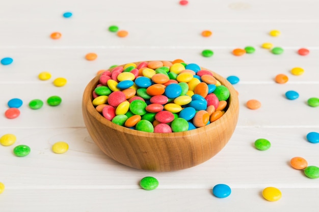 Multicolored candies in a bowl on a colored background birthday and holiday concept Top view with copy space