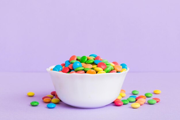 Multicolored candies in a bowl on a colored background birthday and holiday concept Top view with copy space