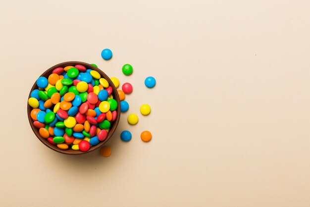 Multicolored candies in a bowl on a colored background birthday and holiday concept Top view with copy space