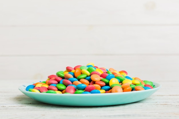 Multicolored candies in a bowl on a colored background birthday and holiday concept Top view with copy space