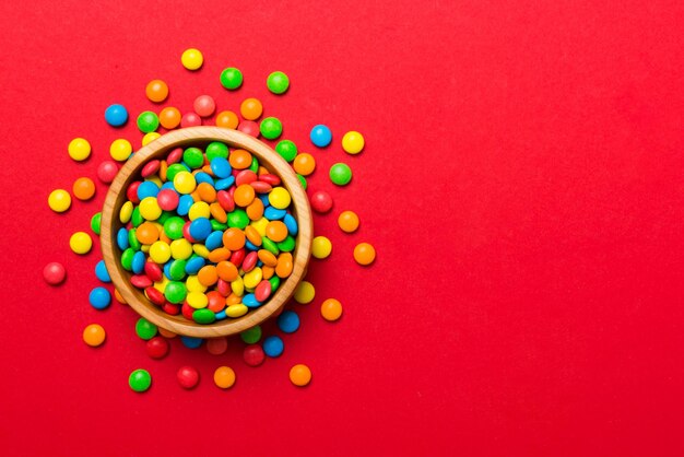 Multicolored candies in a bowl on a colored background birthday and holiday concept Top view with copy space