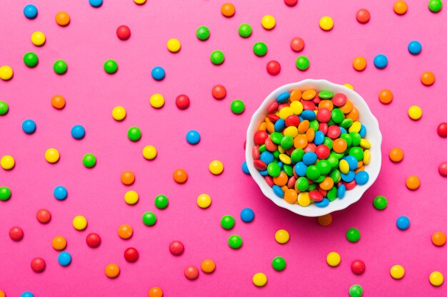 Multicolored candies in a bowl on a colored background birthday and holiday concept Top view with copy space