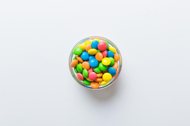 Multicolored candies in a bowl on a colored background birthday and holiday concept Top view with copy space