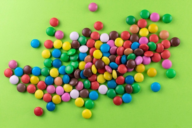 Multicolored candies on a bright green backgroundTop view