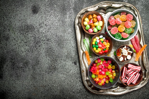 Multicolored candy, jelly and marshmallows in a bowl. On a rustic table.