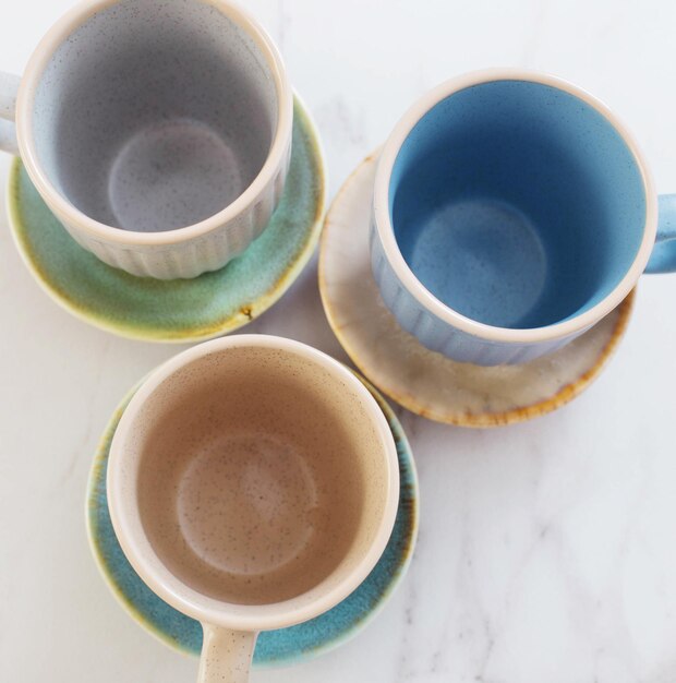 Photo multicolored ceramic cups and plates on white marble table