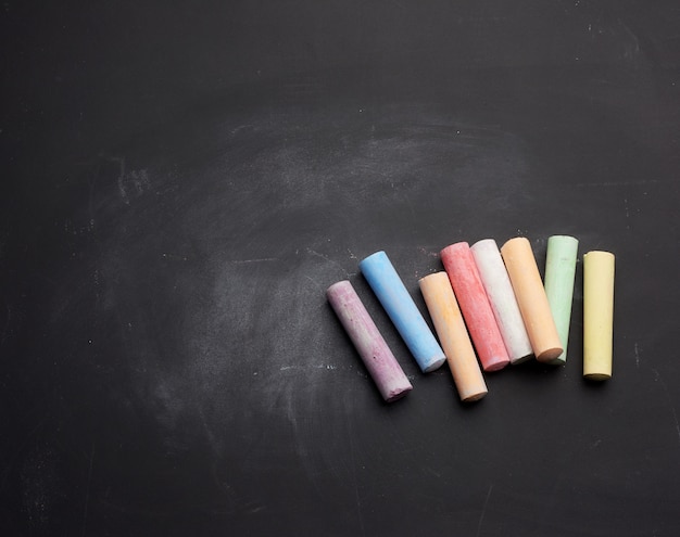 Multicolored chalk on lie on empty black chalk board