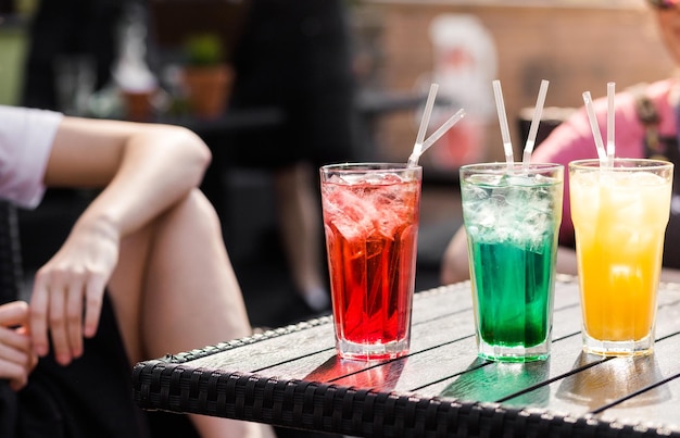 Multicolored cocktails stand on a table on the street terrace of a cafe Hot summer weather