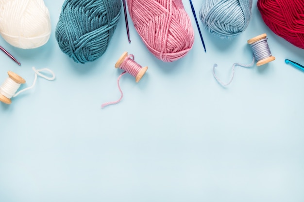 Photo multicolored crochet hooks with balls of yarn on a blue background