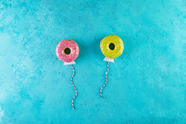 Ciambelle multicolori con glassa e codette a forma di palloncini che volano nel cielo.