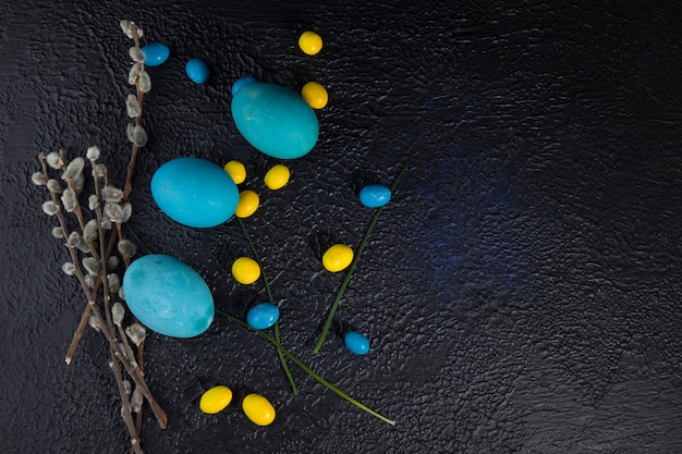 Multicolored easter eggs and pussy willow branches on dark textured background