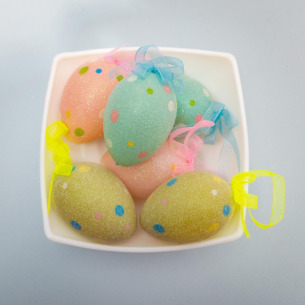 Multicolored Easter eggs in a white square dish, top view.