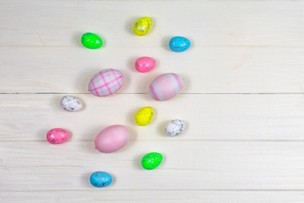 Multicolored Easter eggs on a white wooden table with copy space Flat lay View from above