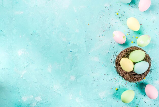 Multicolored Easter eggs with decorative bird's nest and sugar sprinkles on a light blue background,copy space