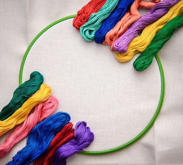 Разноцветная вышивка нитью на фоне вышивки с белым контуром