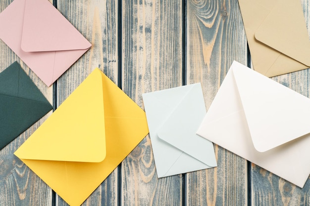 Multicolored envelopes lie randomly on gray wooden background Copy space Top view Mail correspondence