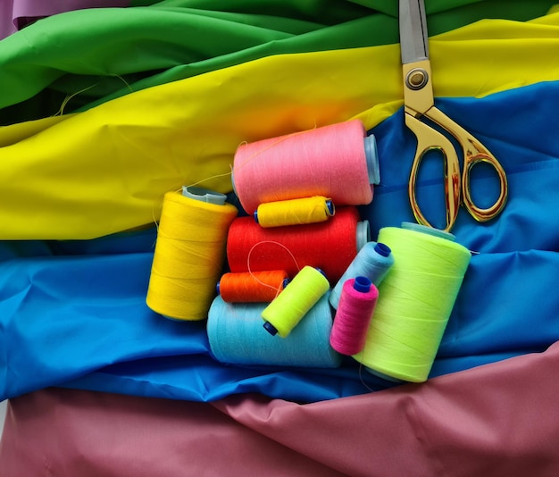 Multicolored fabric threads and scissors in the atelier at workplace