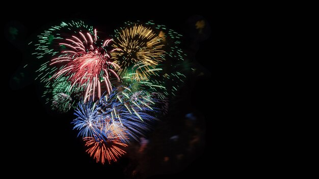 Cuore multicolore dei fuochi d'artificio in cielo nero, spazio della copia