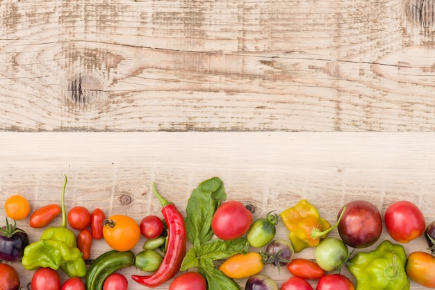 Разноцветные свежие органические овощи, паприка, помидоры и зелень на натуральном деревянном фоне