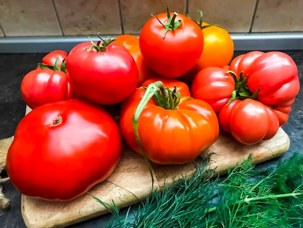 Multicolored fresh tomatoes on wooden kitchen board.