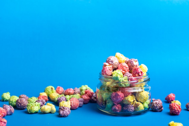 Multicolored fruit flavored popcorn in glass cups on blue