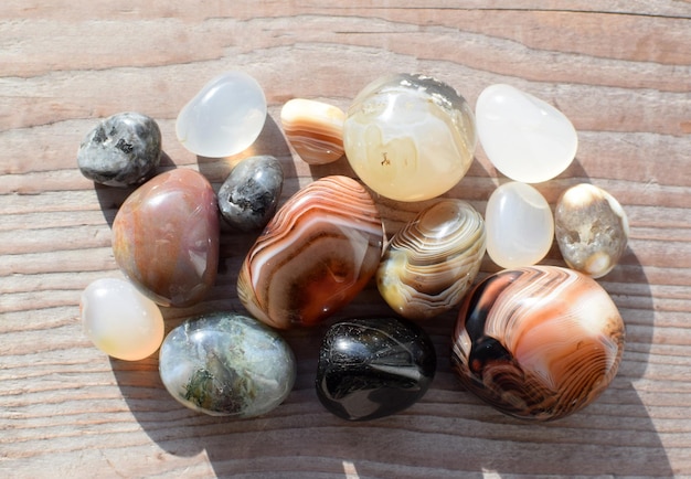 Multicolored gemstones tumbled minerals Bostwan agate of various sizes on a wooden background