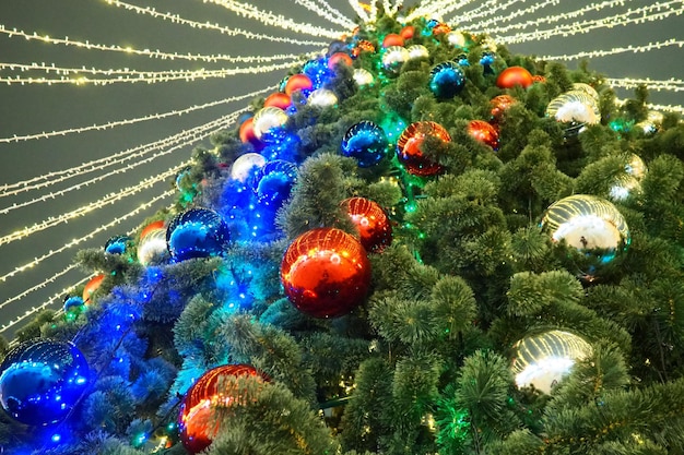 Photo multicolored glass shiny balls on the new years city tree glowing garlands hang over the christmas