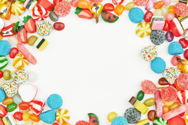 Multicolored gummy candies on a white background Free space in the center Festive frame backdrop