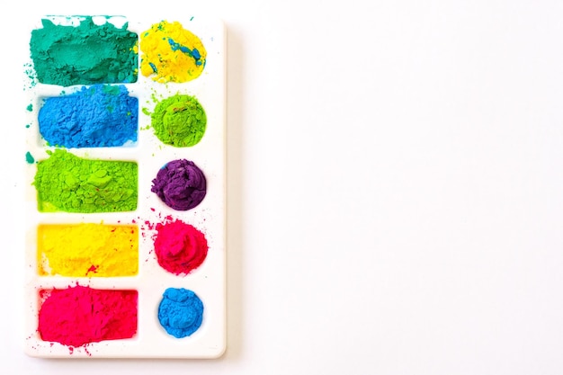 Multicolored holi paints in a palette on a white background from above copy space high quality photo