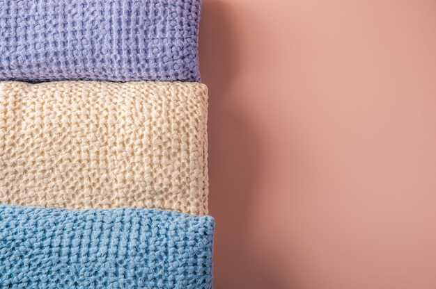Multicolored linen and cotton bath and spa towels twisted into a roll on pink