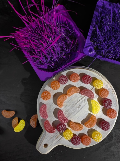 Photo multicolored lollipops on a dark background bright props dominant purple cup and board