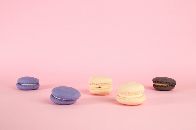 Multicolored macaroni cookies on pink isolated background