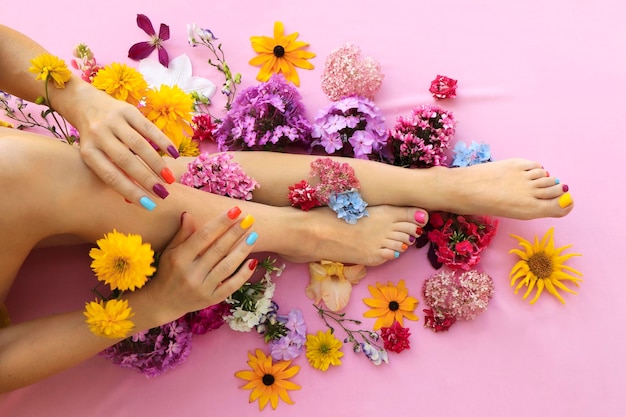 Photo multicolored manicure and pedicure on square shaped nails with different flowers.