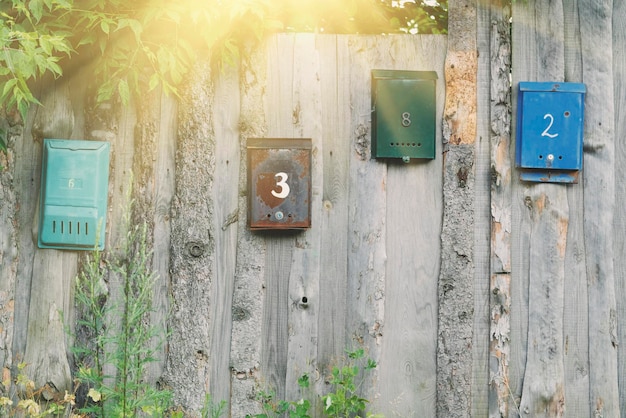 Multicolored metal mailbox on an old wooden fence in the sunlight