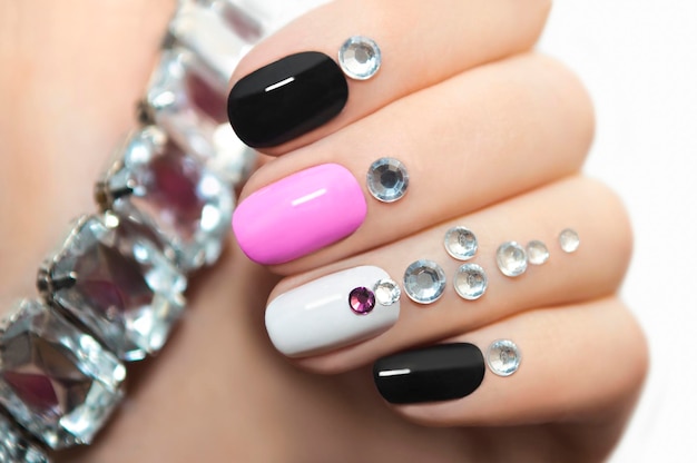 Multicolored nail design with rhinestones.