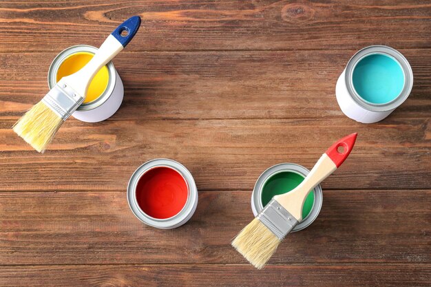 Multicolored paint in tin cans on wooden background top view