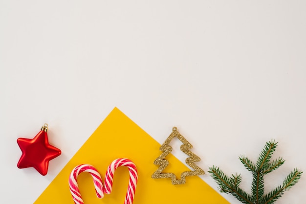 ミント杖、スプルースの枝、創造的なゴールドのクリスマスツリー、トップビューで色とりどりの紙の背景。クリスマスカードの概念。コピースペース