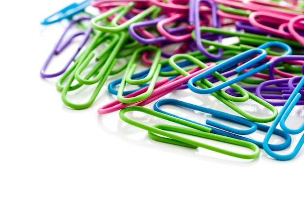 Multicolored paper clips in a pile on a white background.