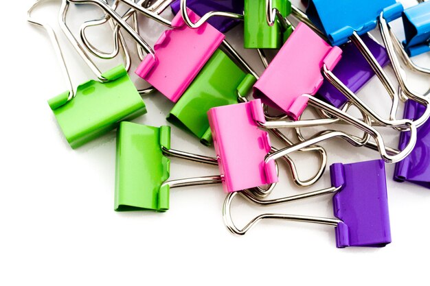 Multicolored paper clips in a pile on a white background.