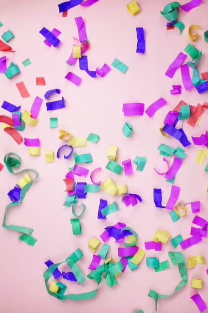 Multicolored paper confetti on a pink background