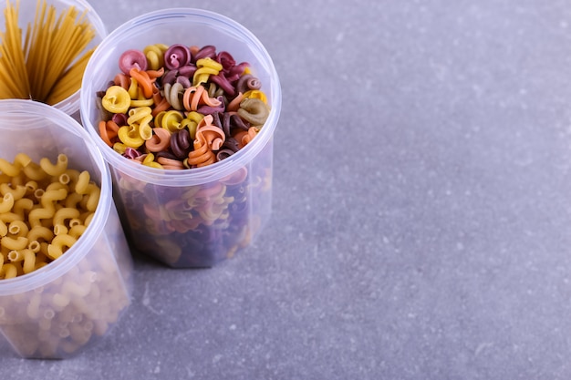 Multicolored pasta with the addition of natural vegetable dye In a jar on a concrete table. Top view, .