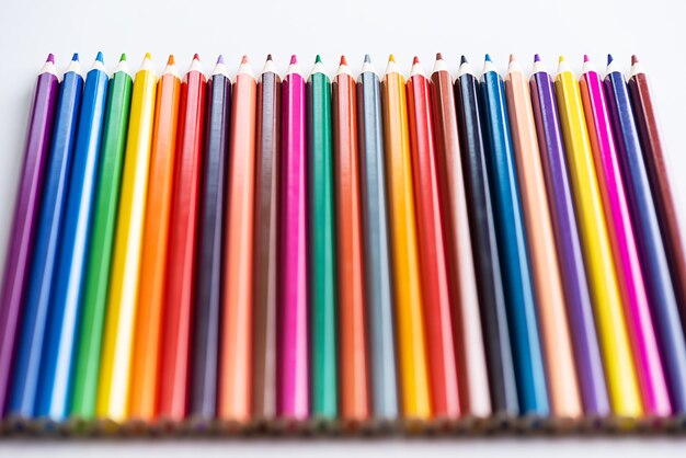 Multicolored pencils in a row on a light background