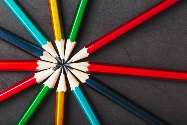 Multicolored pencils in the shape of a star on a black background.