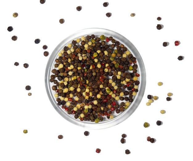 Multicolored peppercorns red green black white pepper in a glass plate on a white background