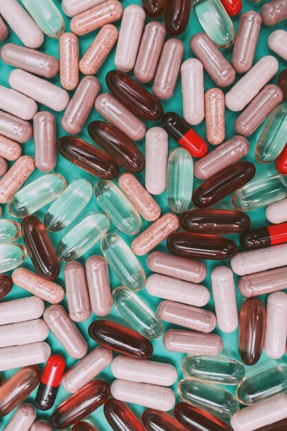 Multicolored pills and capsules on a green background