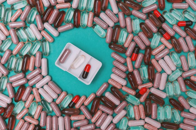 Multicolored pills and capsules on a green background