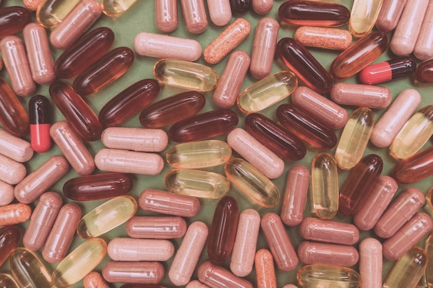 Multicolored pills and capsules on a green background